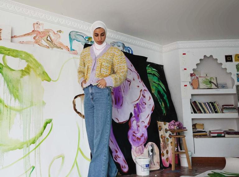 Alymamah Rashed: How Escape for an Artist can be found on the Canvas Alymamah Rashed in front of one of her vibrant, nature-inspired artworks, showcasing the themes of identity, nature, and cultural heritage.