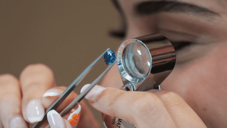 L’ÉCOLE Festival Opens at Dubai Design District, Showcasing the Art of Jewelry A gemologist closely examining a precious gemstone under a magnifying glass, assessing its cut, clarity, and color during a workshop at L’ÉCOLE Festival.